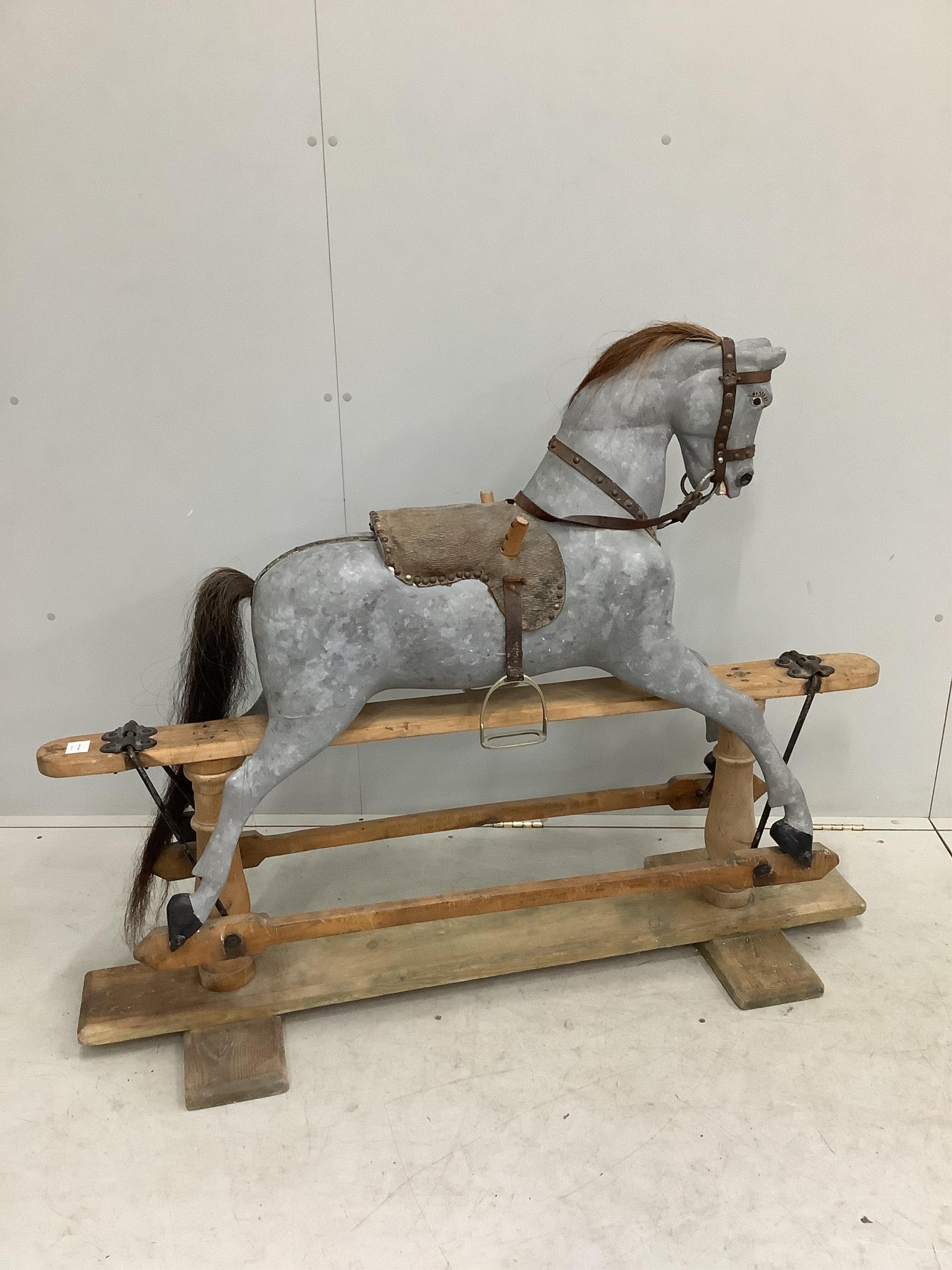 An early 20th century dapple grey rocking horse on pine safety frame, length 136cm, height 108cm. Condition - fair, later painted